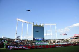 A nuclear-capable B-2 Stealth Bomber flies over a gigantic flag at the 2012 Baseball All-Star Game